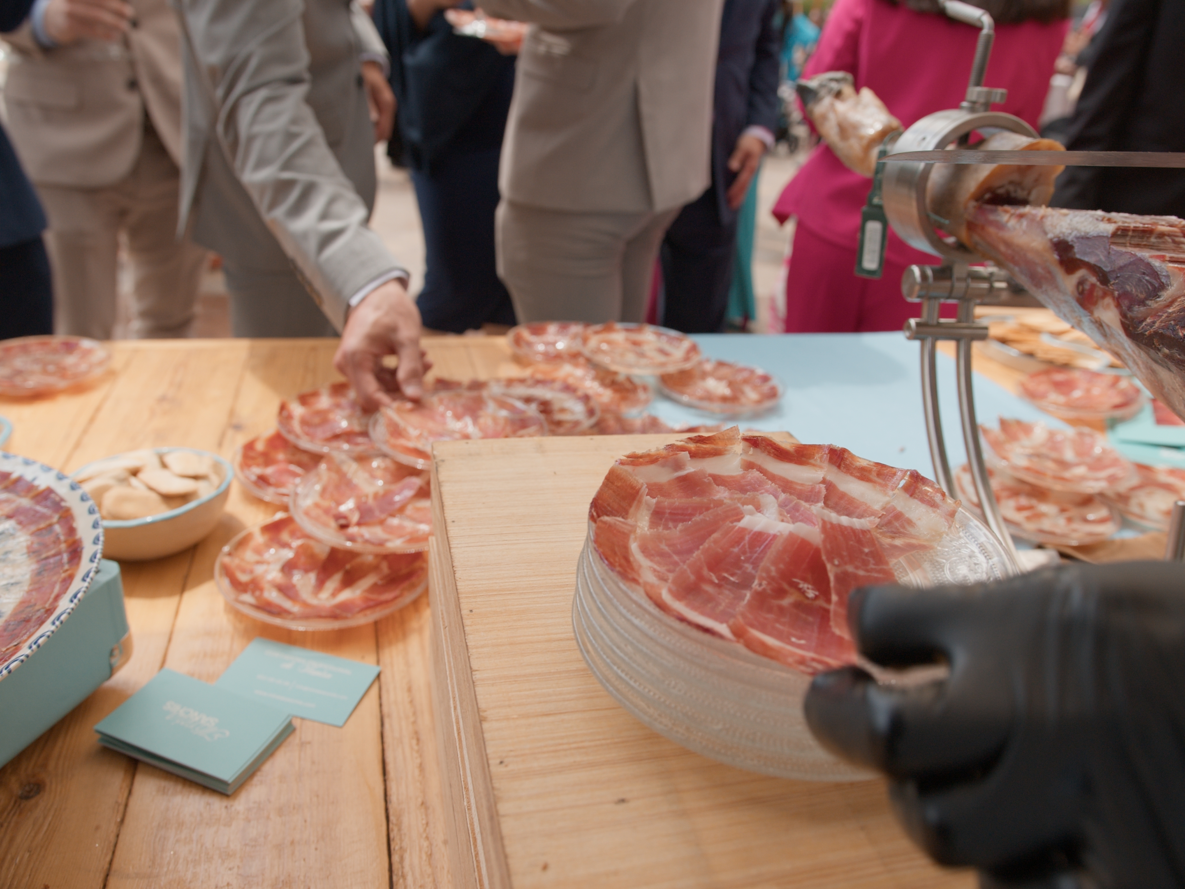 Invitado sirviéndose jamón ibérico recién cortado mientras Mireia Sanchis corta la pieza