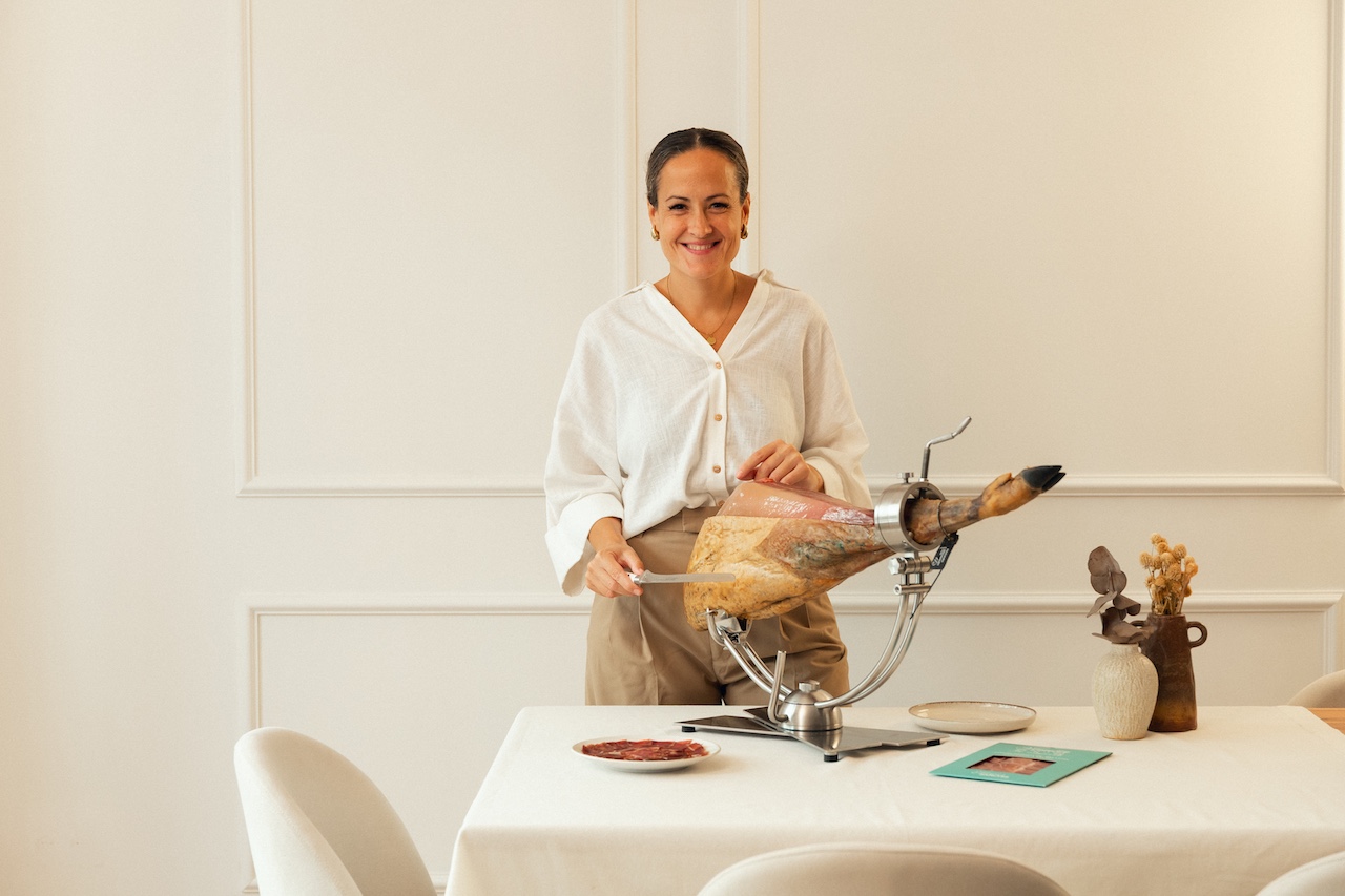 Mireia Sanchis, cortadora profesional de jamón, junto a una pieza de jamón ibérico en el jamonero
